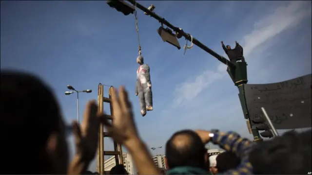 Massa demonstran menyatakan muak dengan atas korupsi, kecurangan politik dan pengangguran di bawah rezim Presiden Mubarak dengan menggantung boneka lambang Mubarak di tiang rambu jalan. 