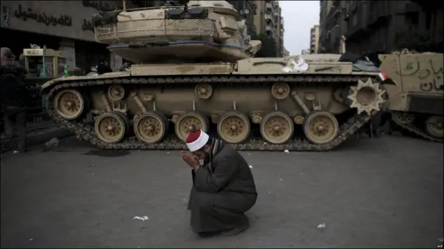 一名反政府示威者在一輛埃及軍隊坦克前祈禱和哭泣（02/02/2011）