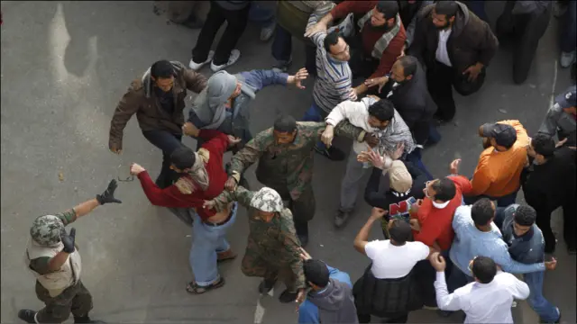 Tentara berusaha melidungi seorang demonstran pro-pemerintah dari amuk massa kubu oposisi.