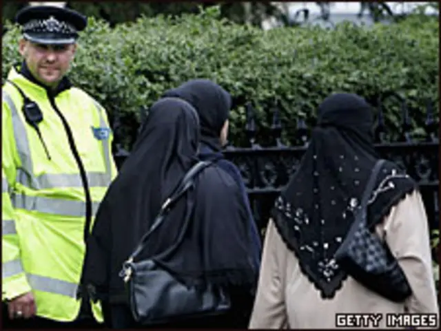 Mujeres musulmanas caminan junto a policías británicos