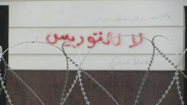 Từ sau hàng rào kẽm gai là dòng chữ "Không chấp nhận cha truyền con nối".