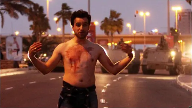 Un ciudadano manchado de sangre parado frente a los tanques del Ejército en las proximidades a la Plaza Perla en Manama.