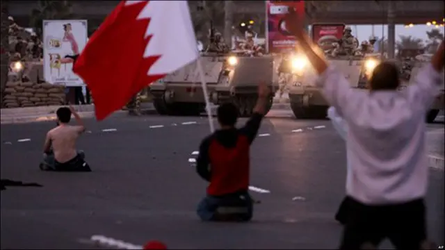 Manifestantes sentados frente a los tanques en Manama, capital de Bahréin.