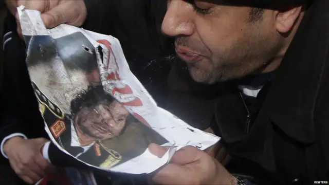 متظاهر ليبي يبصق على صورة للزعيم الليبي معمر القذافي