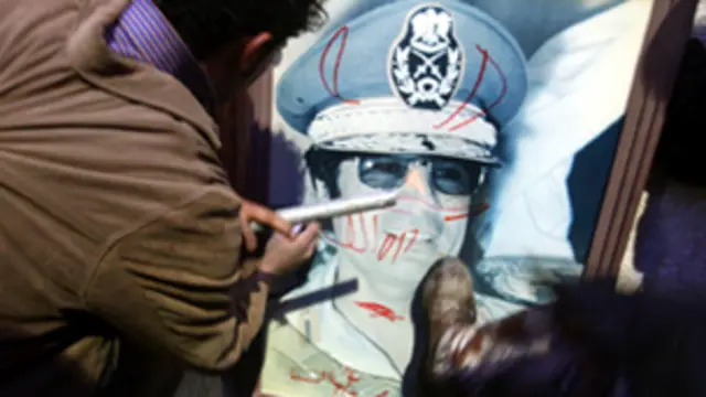 ليبيون يدوسون بأقدامهم صورة للقذافي