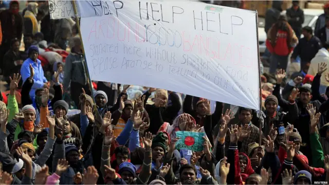 Pekerja pendatang dari Bangladesh di Ras Jdir membentangkan spanduk meminta pertolongan