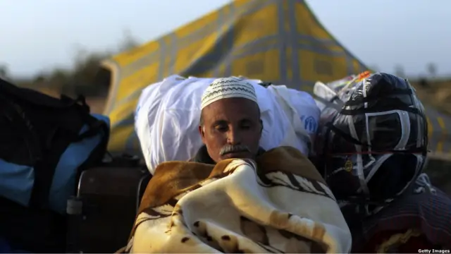 Мужчина спит в палатке для беженцев в Тунисе