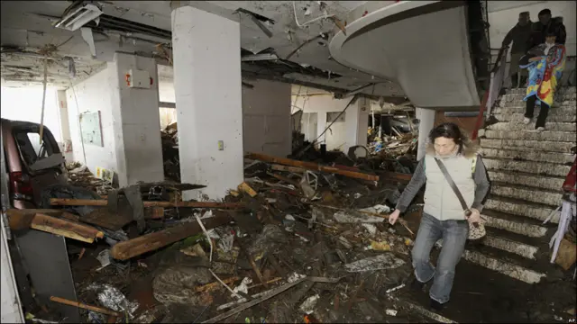 د جاپان په شمال ختيځ سینډای ښار کې تر زلزلې وروسته خلک د لومړني ښوونځي په ړنګه شوې ودانۍ کې ګرځي.