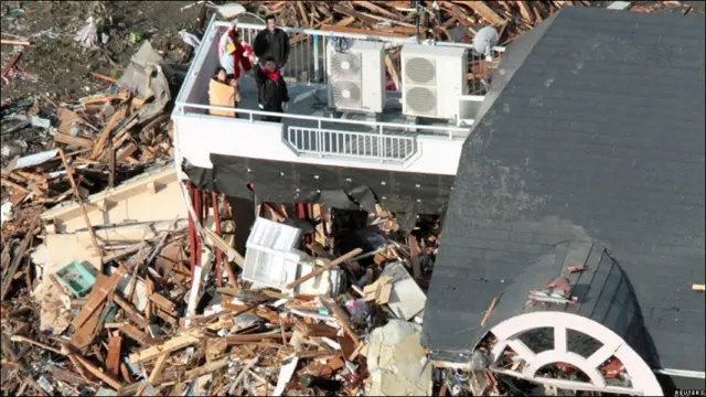 د جاپان په شمال ختيځ کې تر زلزلې وروسته خلک د یوې ودانۍ پر سر د ژغورندویې ډلې په انتظار ولاړ دي.