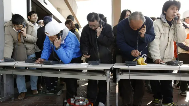 Para penduduk menggunakan layanan telepon umum