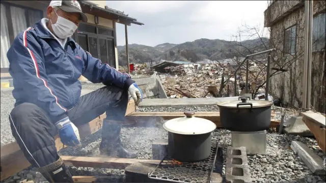 一名决定留在老家的男子正在露天里做饭。