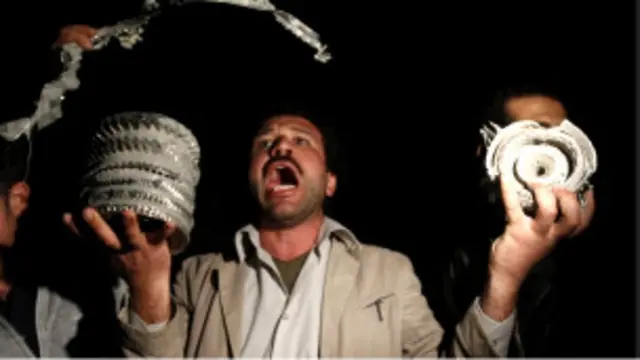 Seorang pendukung Muammar Gaddafi memperlihatkan pecahan misil yang ditembakkan koalisi