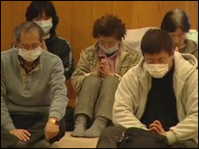 Những người sống sót mất nhà cửa cầu nguyện tại đền thờ nhìn xuống Kamaishi