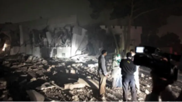 مردم در نزدیکی ساختمان‌های تخریب‌شده باب‌العزیزیه، مقر معمر قذافی در طرابلس گفت‌وگو می‌کنند