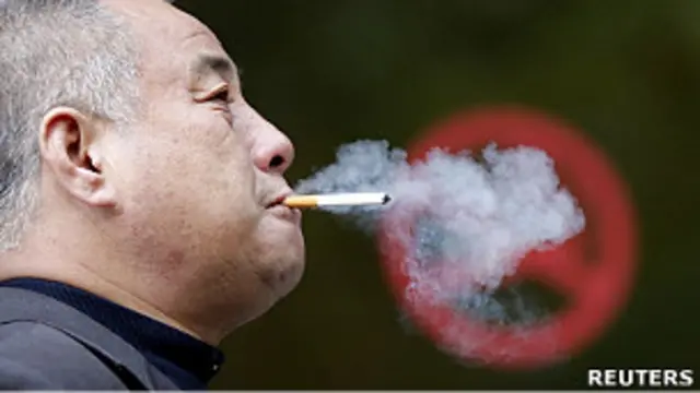 Курильщик в Шанхае напротив надписи "курить запрещено"