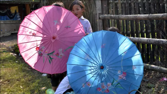 Các bé gái Hmong đang chơi trong vườn nhà với những chiếc ô sặc sỡ màu. Gương mặt ngây thơ, bẽn lẽn khi thấy khách lạ đến làng. 