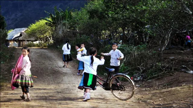 Con đường làng và các em bé Hmong. Một số em đã biết đi xe đạp, thay vì đi bộ nhiều cây số đến trường. Làng này vẫn chưa có điện dù cách đường quốc lộ chưa tới 10 cây số. Họ vẫn xài đèn dầu và bình ắc quy. 