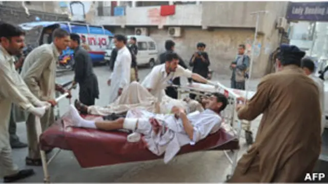 Petugas kesehatan membawa korban bom bunuh diri di sekolah paramiliter di Pakistan.