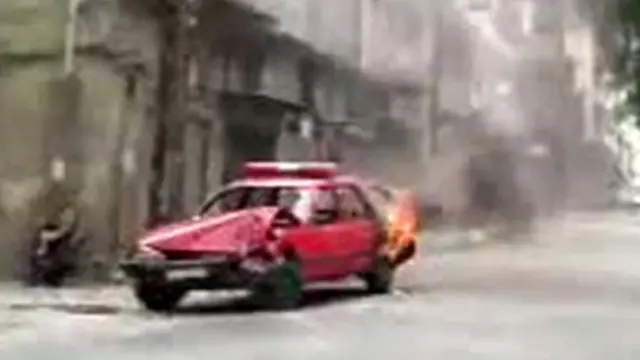 Sebuah mobil polisi terbakar di salah satu sudut kota Homs