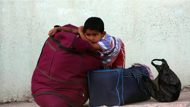 Bocah menunggu dengan barang bawaan di Rafah