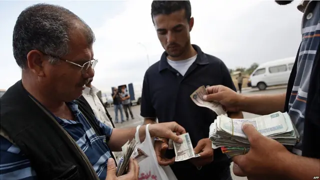 Warga Palestina menukar uang di Rafah