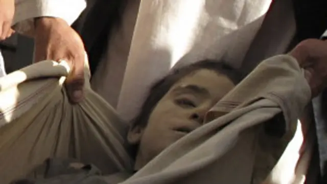 Warga desa menunjukkan sebagian mayat korban pasca serangan di Helmand