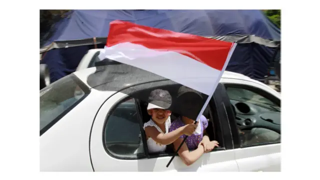 Dua bocah perempuan melambaikan bendera Yaman dari mobil.
