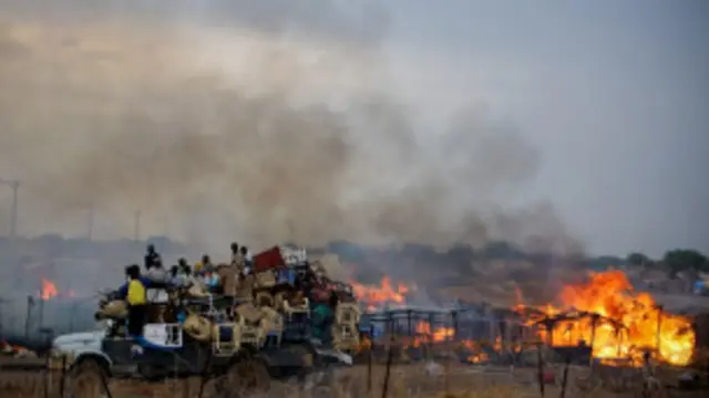 Sebuah truk melewati deretan rumah yang hangus akibat pemboman di Kordofan Selatan.