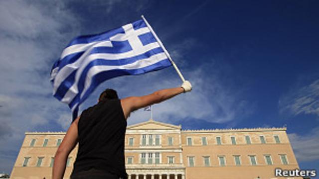 Un joven sostiene una bandera griega.