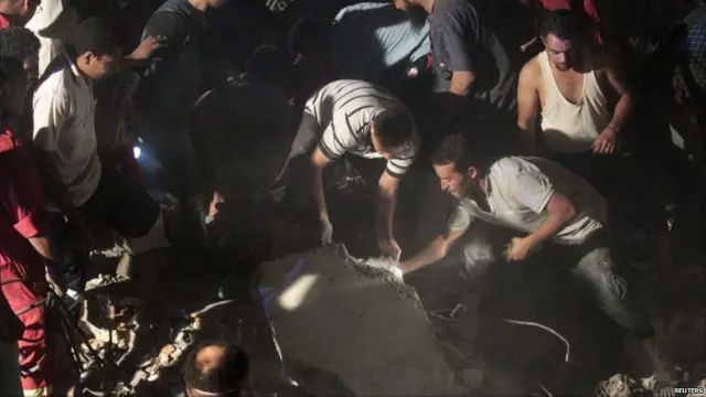 Penduduk setempat membantu petugas mengangkat puing.