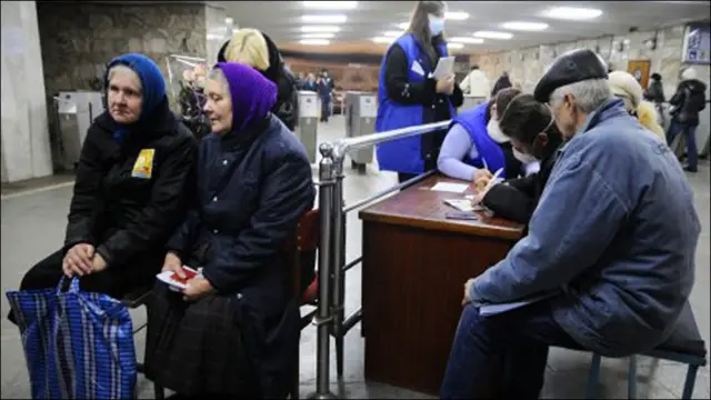 Харківські пенсіонери сидять у черзі, щоб отримати картку на безкоштовний проїзд у метро. 