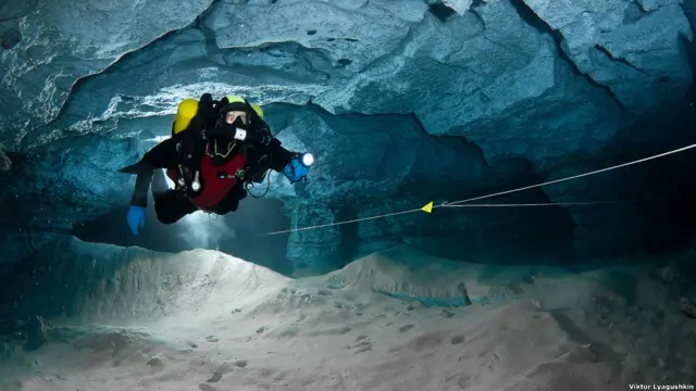 Водолаз плывет насквозь через пещеру