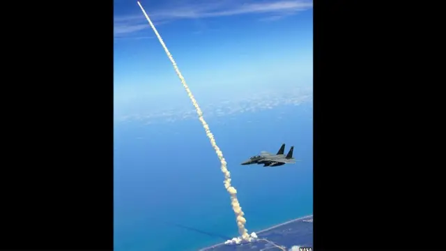 Самолет F15-E патрулирует небо в день старта шаттла "Атлантис"