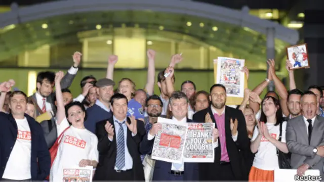 Staf News of the World memperlihatkan edisi terakhir di depan kantor mereka