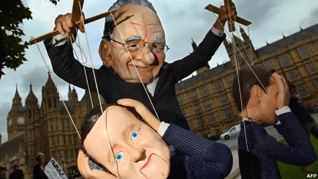 Манифестант в маске Руперта Мердока и с куклой, изображающей Дэвида Кэмерона, в Лондоне