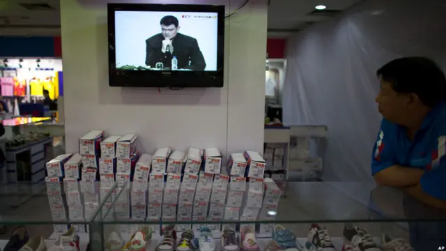 Seorang penjaga toko peralatan olahraga di Beijing menyempatkan diri menonton jumpa pers pengunduran diri Yao Ming.