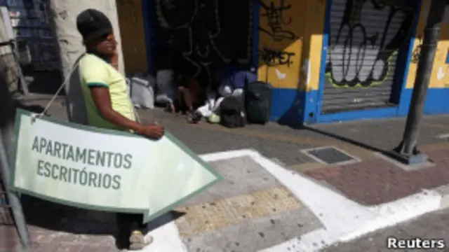 Mulher segura placa de anúncio de imóvel em São Paulo