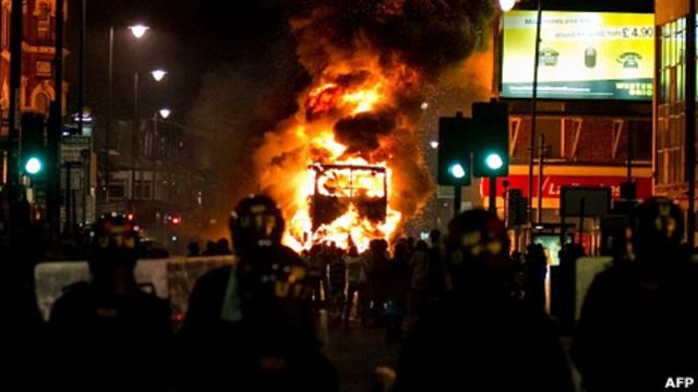 伦敦托特纳姆区骚乱现场一辆双层巴士在防暴警察面前焚烧（6/8/2011）