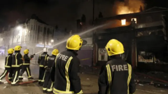 Pemadam kebakaran mencoba mengatasi api yang menghanguskan sebuah toko. 