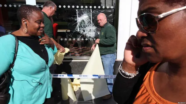 Лондонцы идут мимо ограбленного магазина в Брикстоне