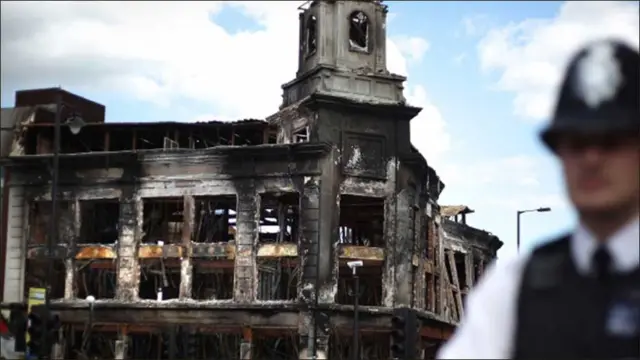 پولیس اہلکار ٹوٹنہم میں نذر آتش ہونے والی عمارت کے بار پہرہ دے رہا ہے۔