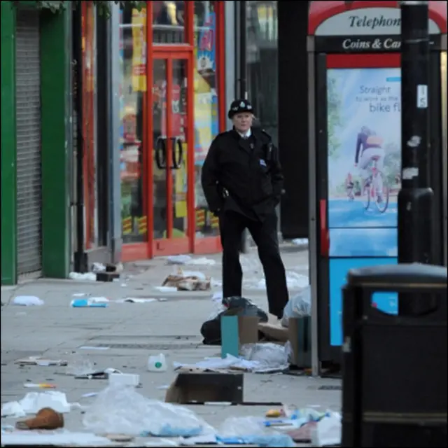 ایک پولیس اہلکار کلیپہم جنکشن کے قریب سینٹ جونز روڈ پر ہونے والے نقصانات کا اندازہ لگا رہا ہے۔