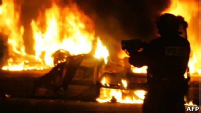 Policial diante de carros em chamas no subúrbio de Clichy-sous-Bois, em Paris, em 2005.