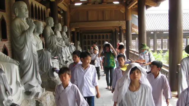 Các đoàn thiếu niên không mang khăn quàng đỏ mà khoác áo kiểu Phật giáo đi lại rất đông trong khu hành lang dài rộng của chùa.