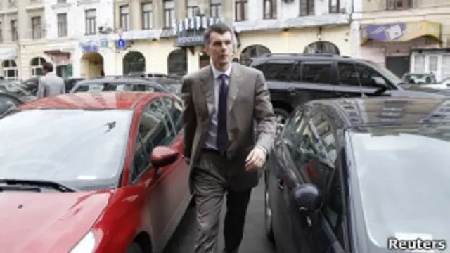 Прохоров идет между двумя машинами