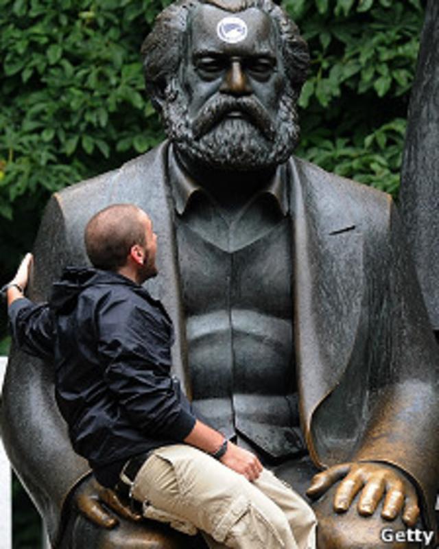 Chico sentado en las piernas de la estatua de Marx