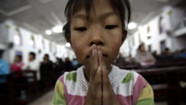 एक चर्च में प्रार्थना करती एक बच्ची