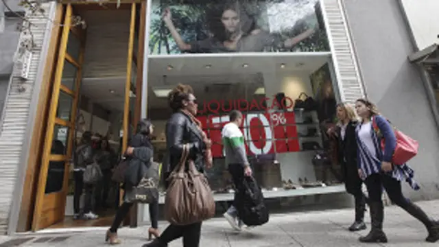 mulheres passam em frente a loja | Foto: AP