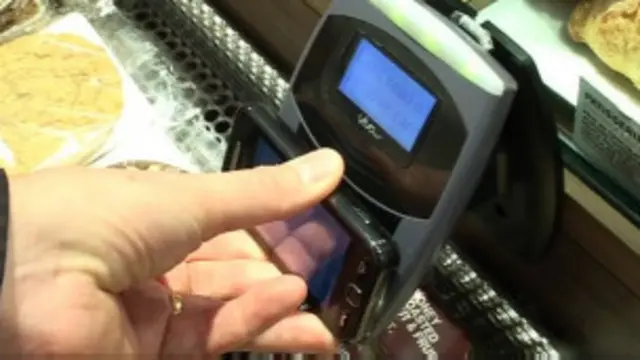 Un consumidor pega su celular a un lector inalámbrico