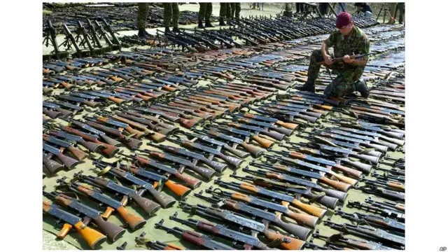 2001 йил 3 сентябри. Македониянинг Юнонистон ҳарбийлари жойлаштирилган Криволак базаси. Британия армияси зобити албан жангариларидан мусодара қилинган Калашников автотматларини кўриб чиқмоқда.